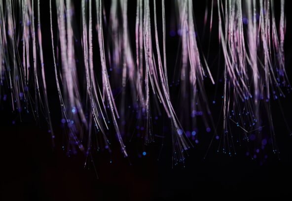 Abstract image of ethereal fiber optic strands cascading with glowing blue lights.