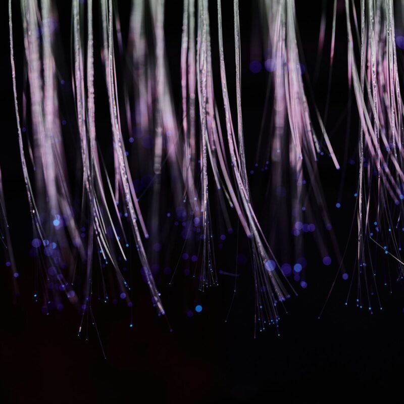 Abstract image of ethereal fiber optic strands cascading with glowing blue lights.