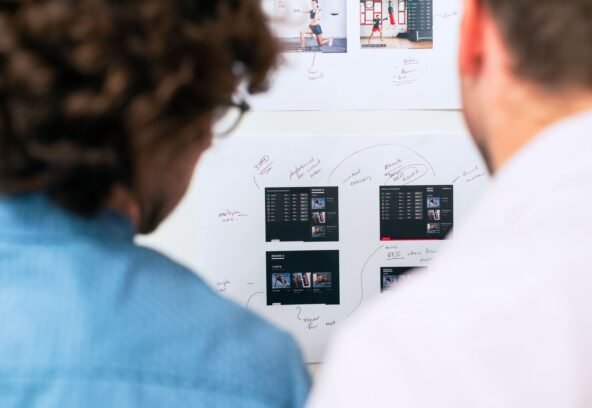 Two business professionals brainstorming and planning software development with a whiteboard in an office.