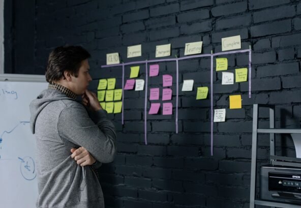 Adult male focusing on task planning using sticky notes on a black wall in a contemporary office setting.