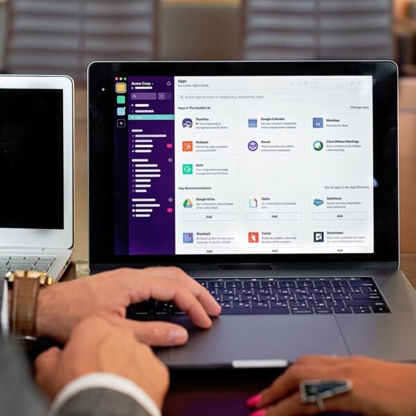 Two professionals collaborating using laptops and communication software in a business setting.