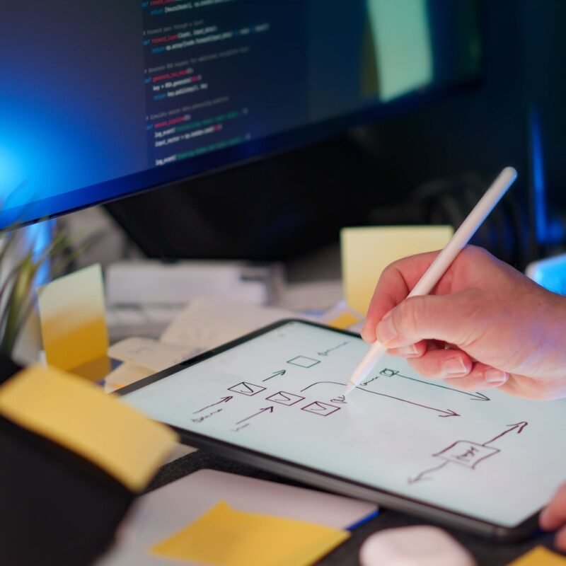 A vibrant workspace featuring digital sketching on a tablet and code on a monitor, showcasing a tech-savvy environment.