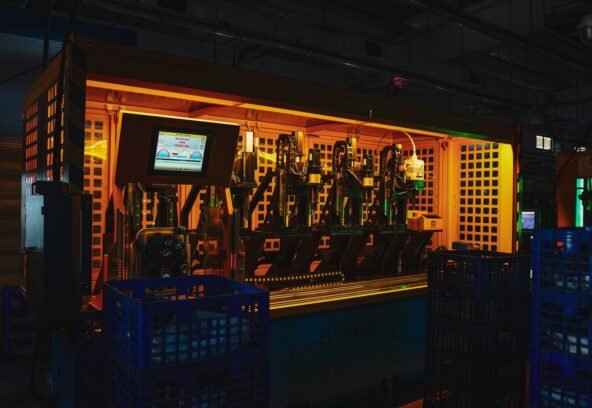 A complex piece of machinery in a dark industrial setting with vibrant lighting.