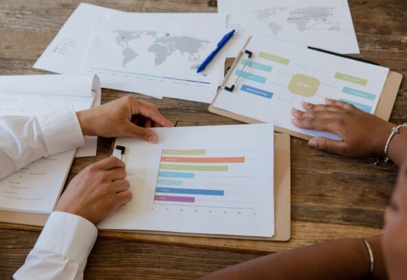pexels-9034283 Top view of colleagues discussing charts and graphs on a wooden table during a business meeting.